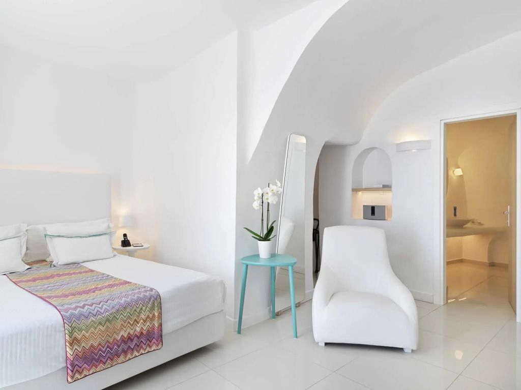 Helle Junior-Suite mit Doppelbett und zeitgenössischem Dekor in Weiß und Pastelltönen.