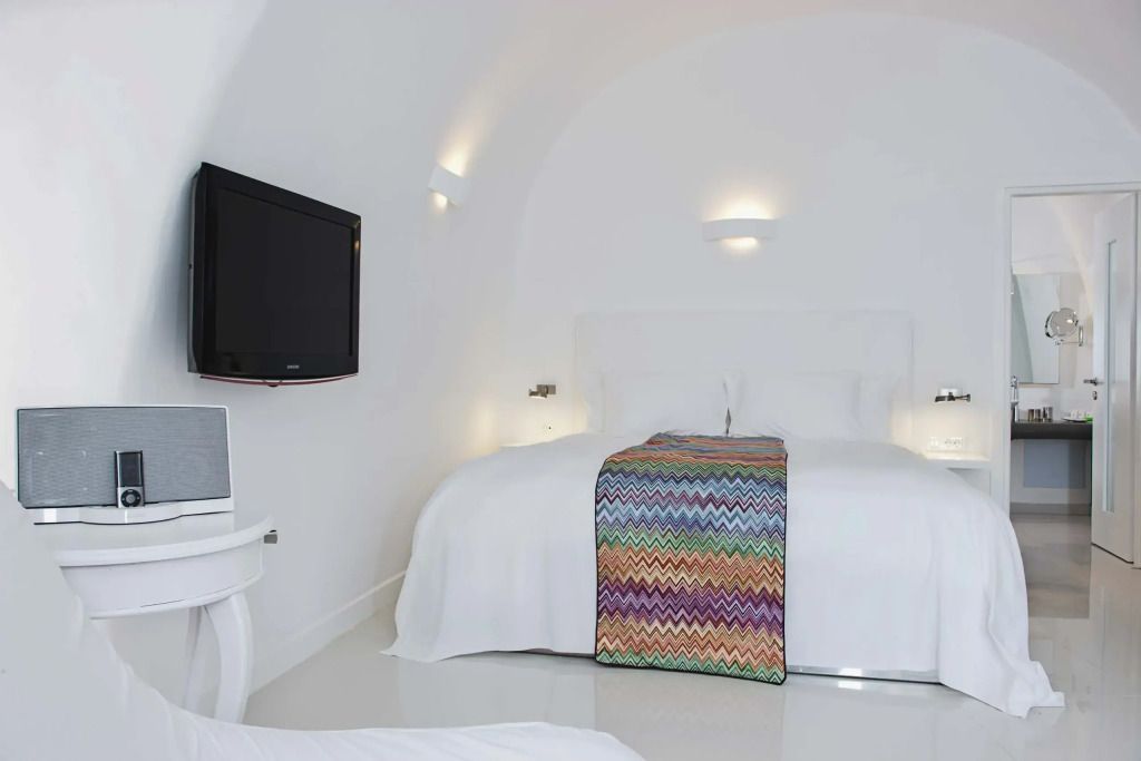 Helles Schlafzimmer mit Doppelbett und farbigem Überwurf in eleganter Suite.