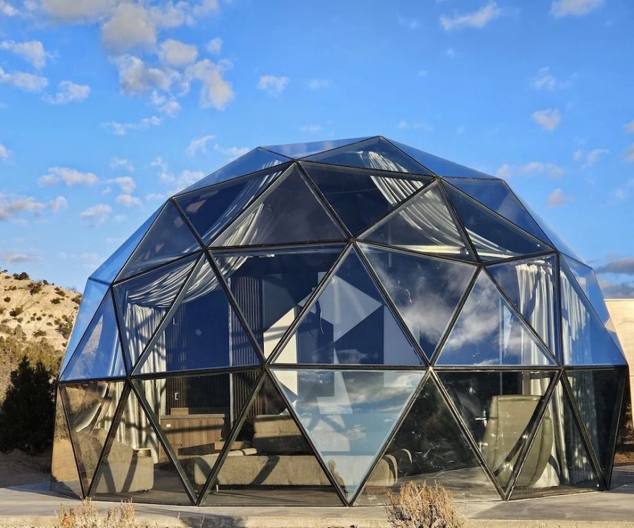 Geodätische Kuppel unter klarem Himmel mit Glasstruktur und Wüstenlandschaft im Hintergrund