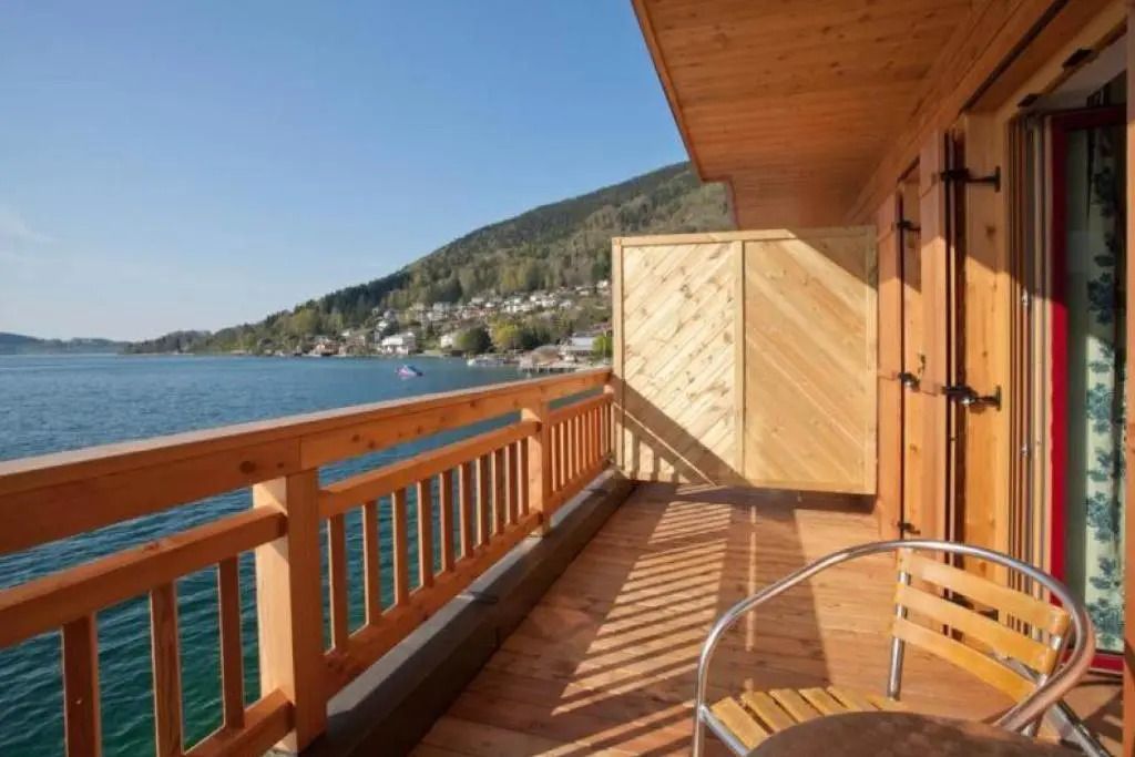 Blick von einem Balkon auf einen See mit Bergpanorama im Hintergrund