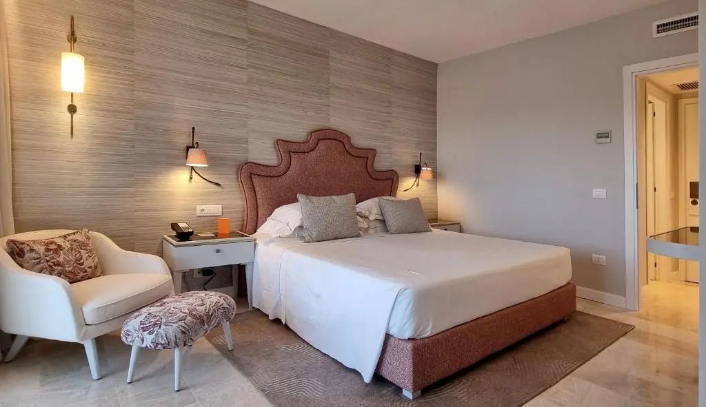 Elegantes Schlafzimmer in der Junior-Suite des CPH Pevero Hotels mit gemütlichem Bett und stilvollen Möbeln