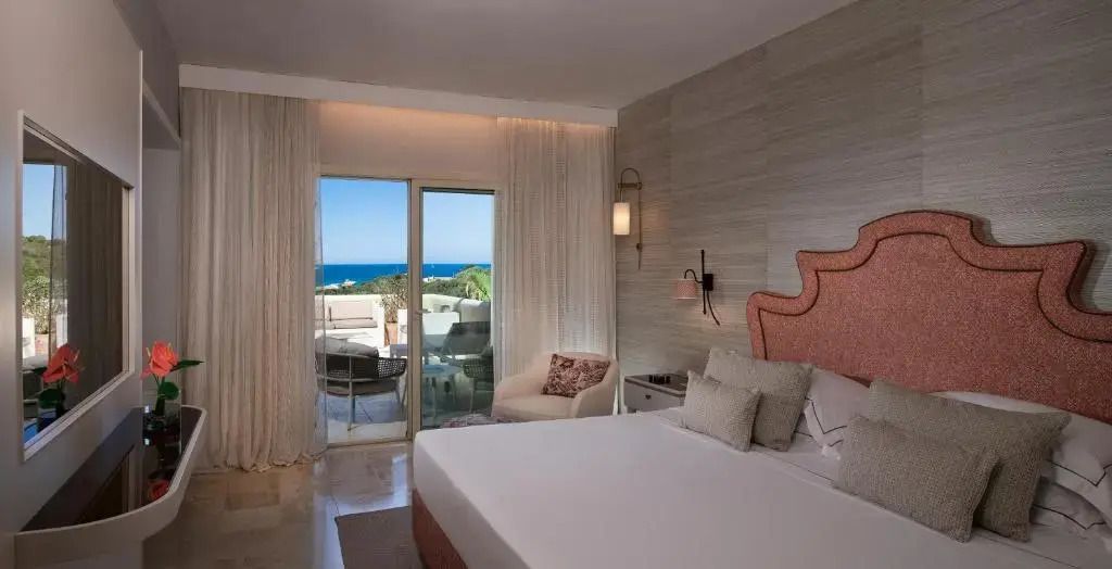Junior-Suite mit Blick auf das Meer, modernen Möbeln und großen Fenstern im CPH Pevero Hotel