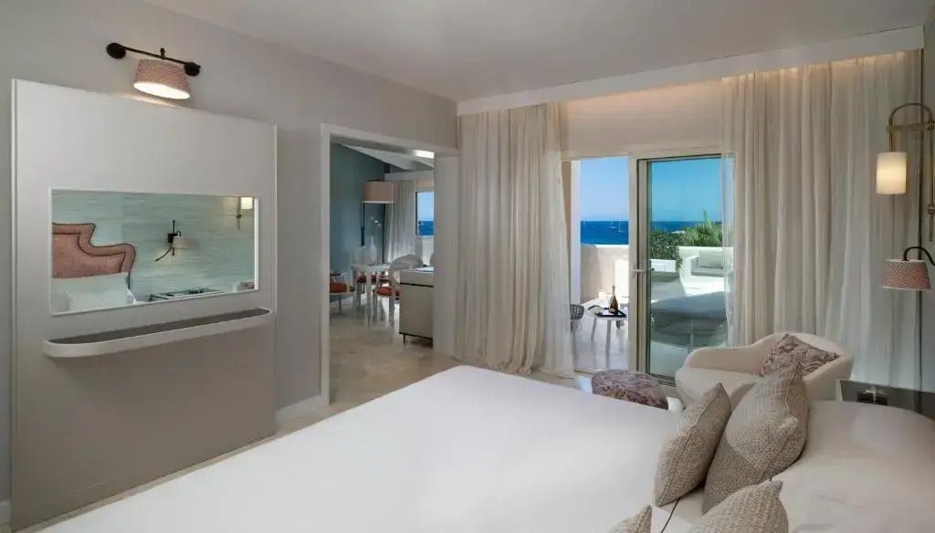 Interieur der Junior-Suite im CPH Pevero Hotel mit Zugang zur Terrasse und Meerblick