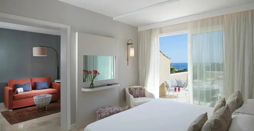 Helles Schlafzimmer mit Balkon und Meerblick im CPH Pevero Hotel