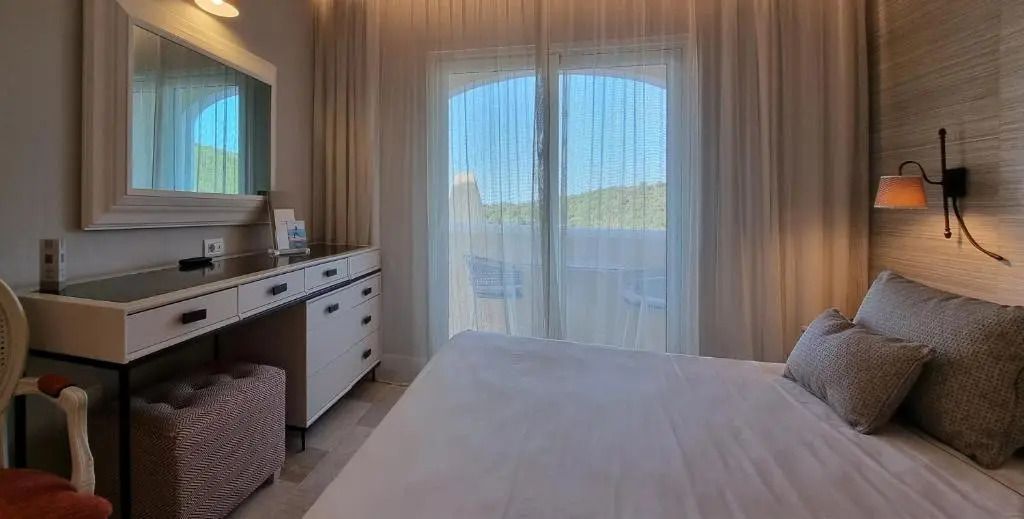 Schlafzimmer mit Vorhängen und Balkonblick im CPH Pevero Hotel