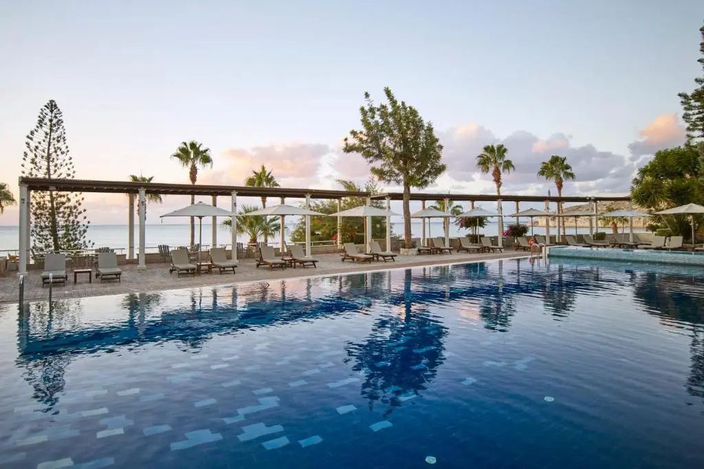 Großer Hotelpool mit Liegestühlen und Blick auf das Meer bei Sonnenuntergang im Columbia Beach Resort