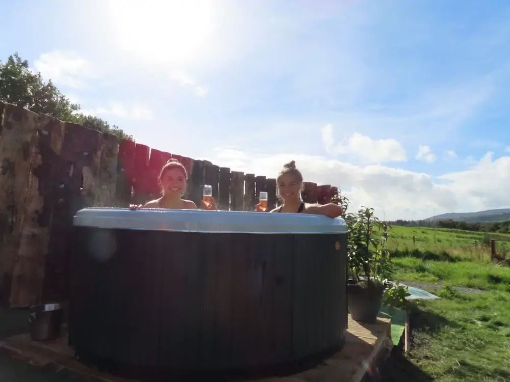 Zwei Personen im Whirlpool mit Getränken an einem sonnigen Tag