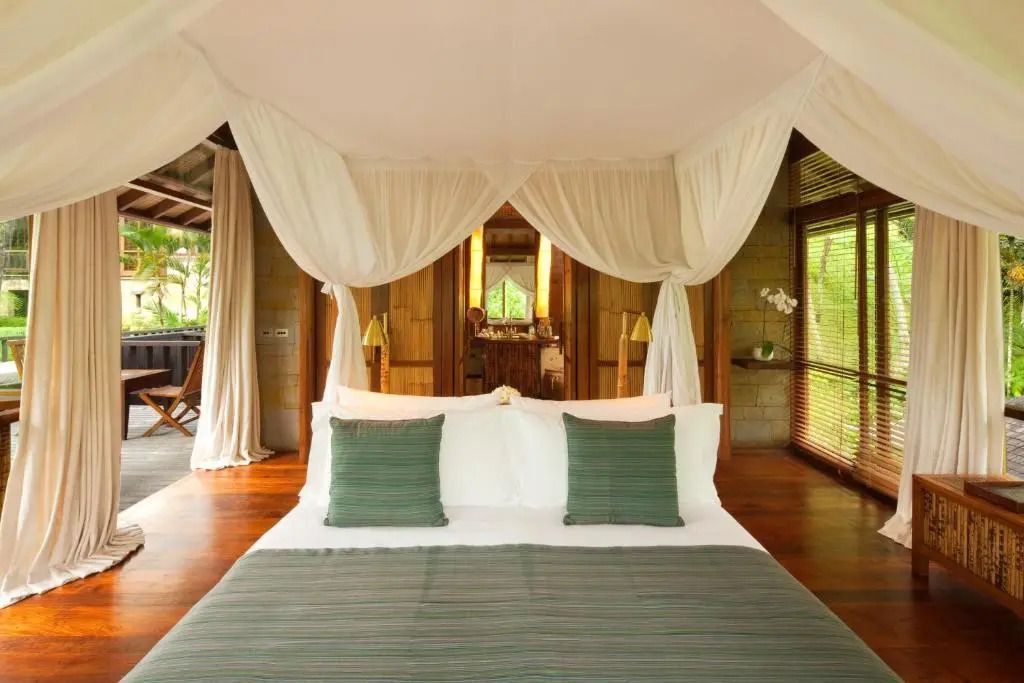 Luxuriöses Himmelbett mit grüner Bettwäsche und Blick in den Garten