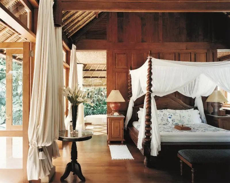 Geräumige Suite mit Himmelbett und Holzelementen. Balkonblick auf grünen Garten
