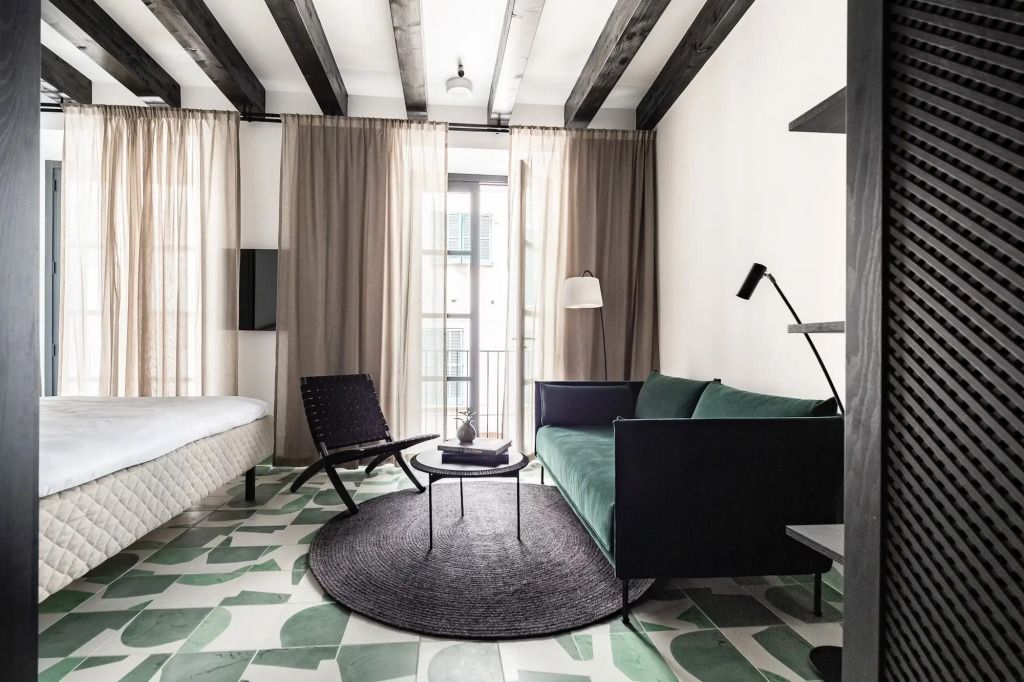 Wohnbereich mit Sofa, Sessel und großen Fenstern im Deluxe Doppelzimmer