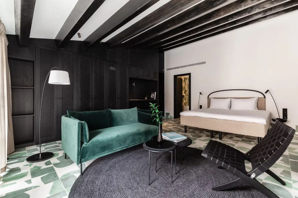 Elegantes Hotelzimmer mit grünem Sofa, Doppelbett und modernem Design