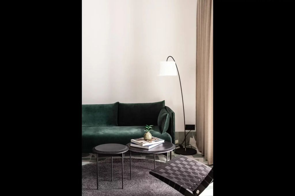 Gemütliche Sitzecke mit grünem Sofa und eleganter Lampe in der Junior-Suite