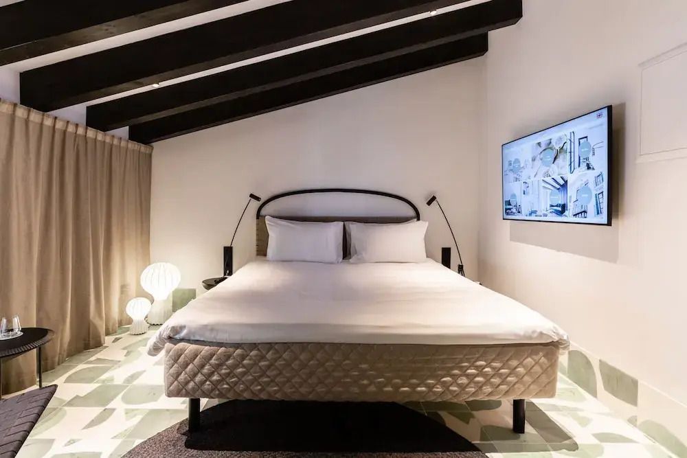 Komfortables Doppelbett in modernem Dachzimmer mit TV und dekorativer Beleuchtung