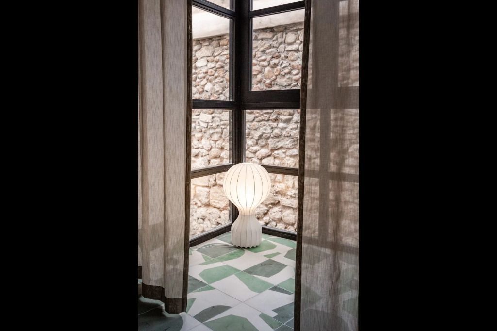 Stilvolle Ecke mit Designerlampe und Steinwand neben bodentiefen Fenstern