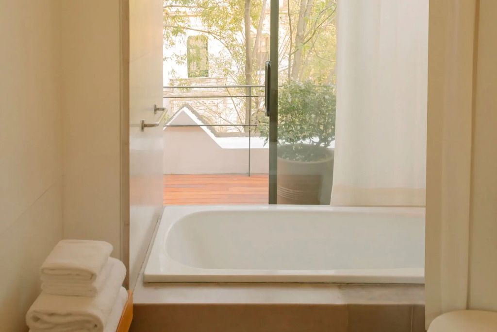 Luxuriöses Badezimmer mit Badewanne und Blick auf Balkon.