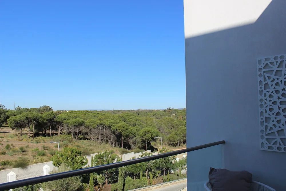 Ausblick vom Balkon auf einen grünen Wald unter blauem Himmel