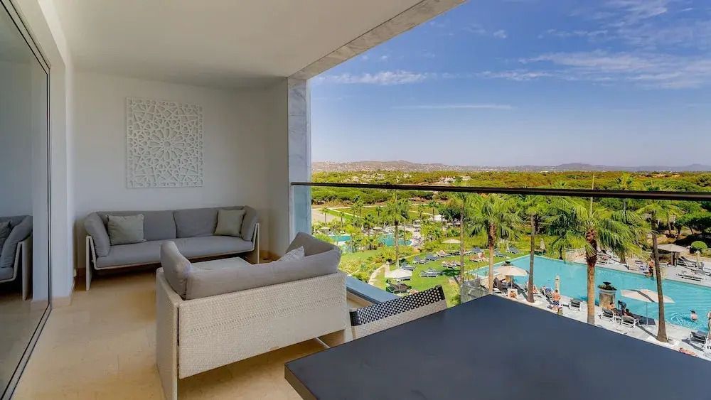 Balkon mit Sitzgelegenheiten und Blick auf den Pool und Garten