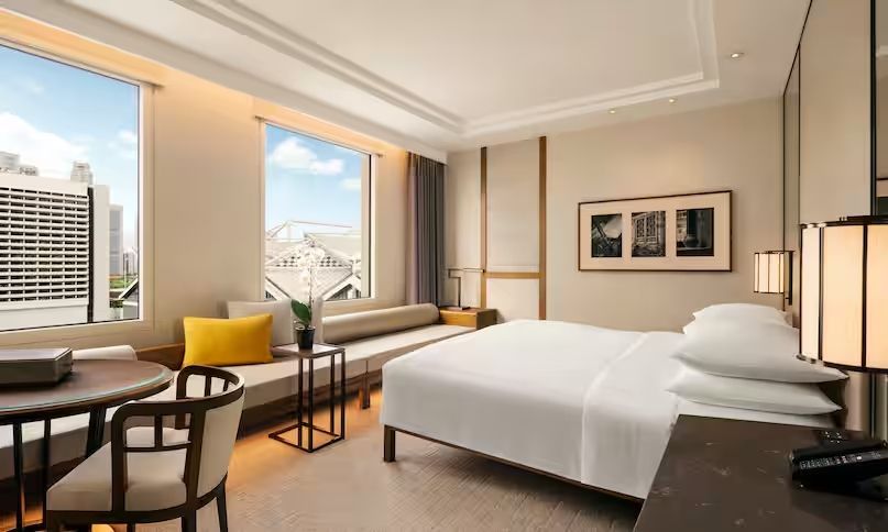 Helles Hotelzimmer mit Doppelbett und Stadtblick durch großes Fenster
