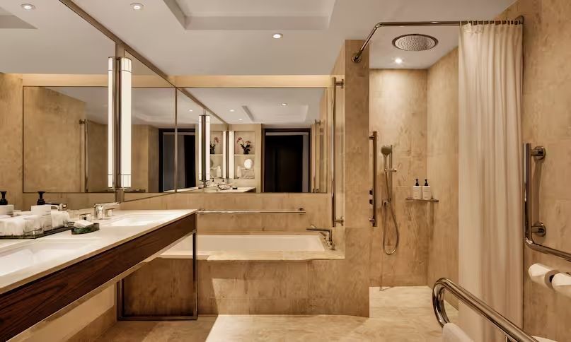 Luxuriöses Badezimmer mit Badewanne und Regendusche in hellem Marmor