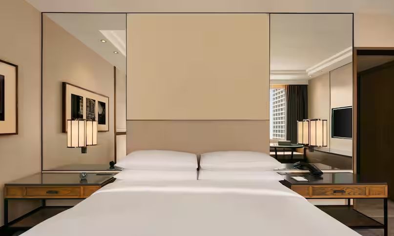 Modernes Doppelzimmer mit zentralem Doppelbett und stilvoller Beleuchtung.