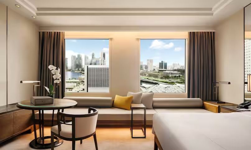 Hotelzimmer mit Sitzbereich und spektakulärem Blick auf die Skyline von Singapur.