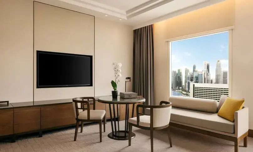 Sitzbereich mit Tisch, Stühlen und Blick auf die Skyline in einem Hotelzimmer.