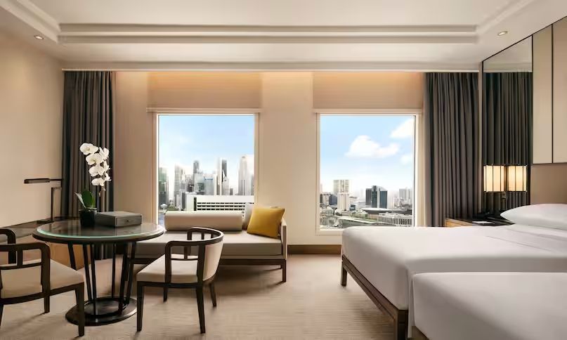 Schlafzimmer mit Sitzgelegenheit und großen Fenstern mit Stadtblick