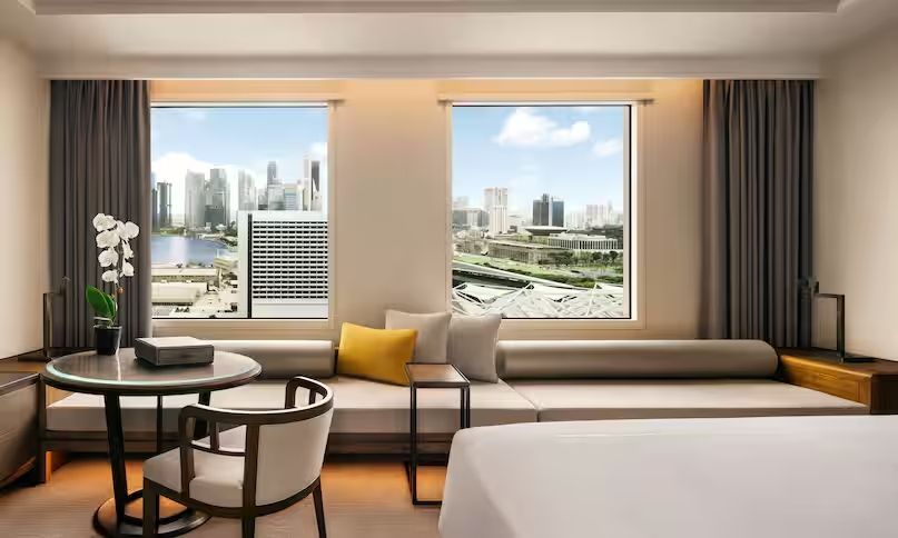 Helles Zimmer mit Doppelbett und Panoramafenster mit Stadtblick.