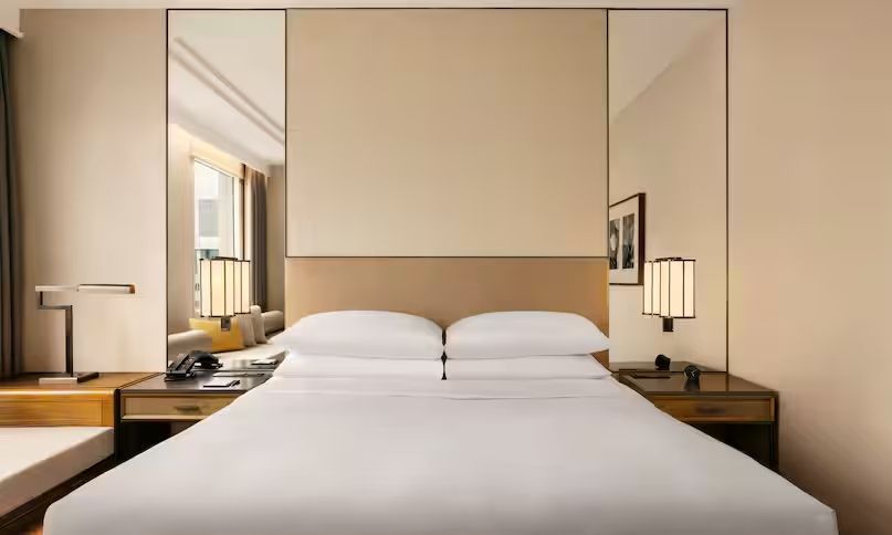 Elegantes Doppelbett mit minimalistischem Nachttisch im Hotelzimmer