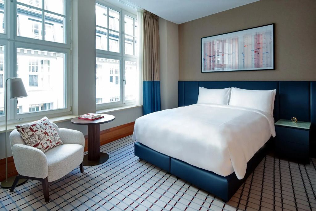 Deluxe Doppelzimmer mit Doppelbett, gepolstertem Sessel und Fenster