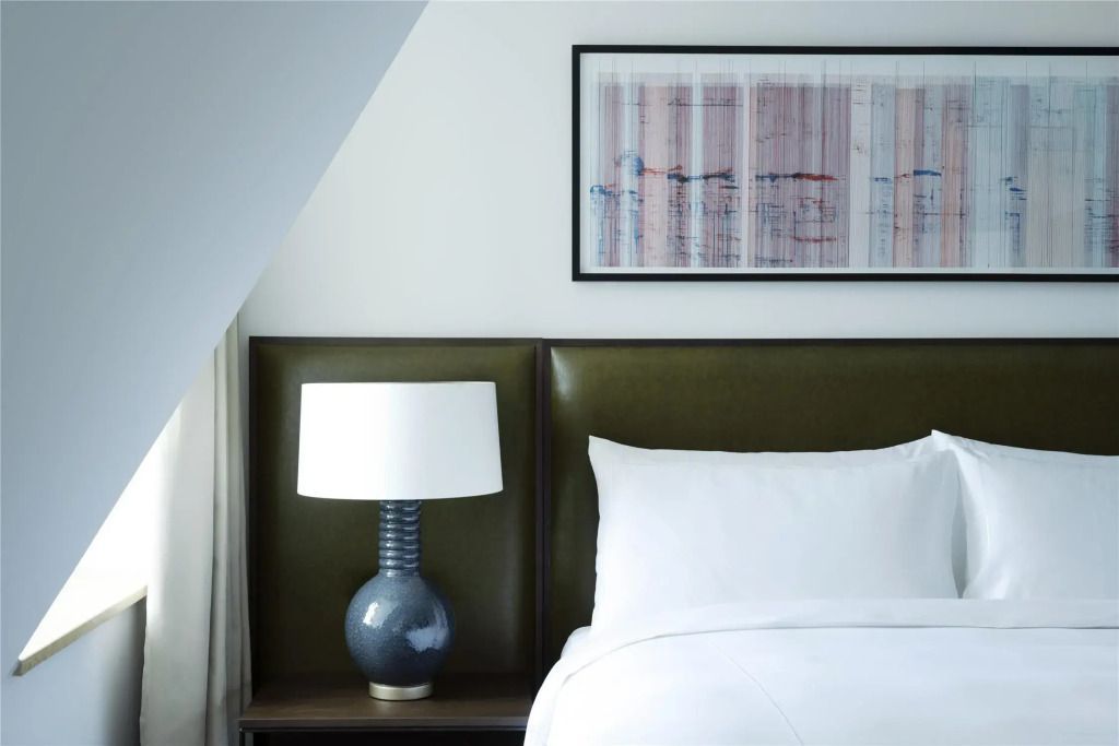 Detailaufnahme eines Bettes mit grüner Lederrückwand und eleganter Tischlampe