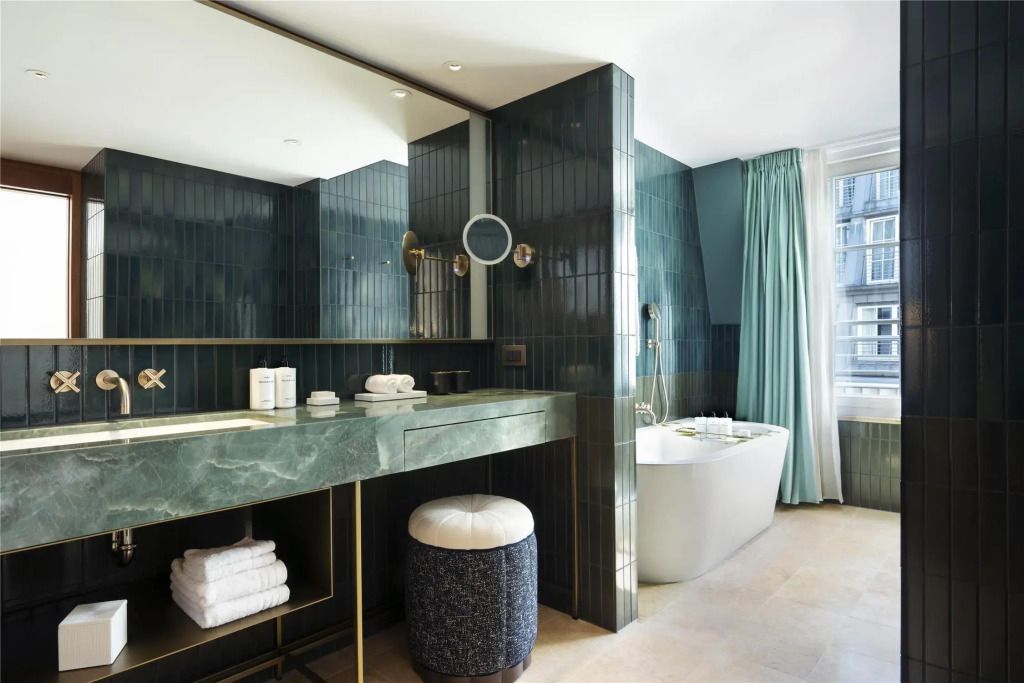 Luxuriöses Badezimmer der Doppel Junior-Suite mit grünen Fliesen und freistehender Badewanne