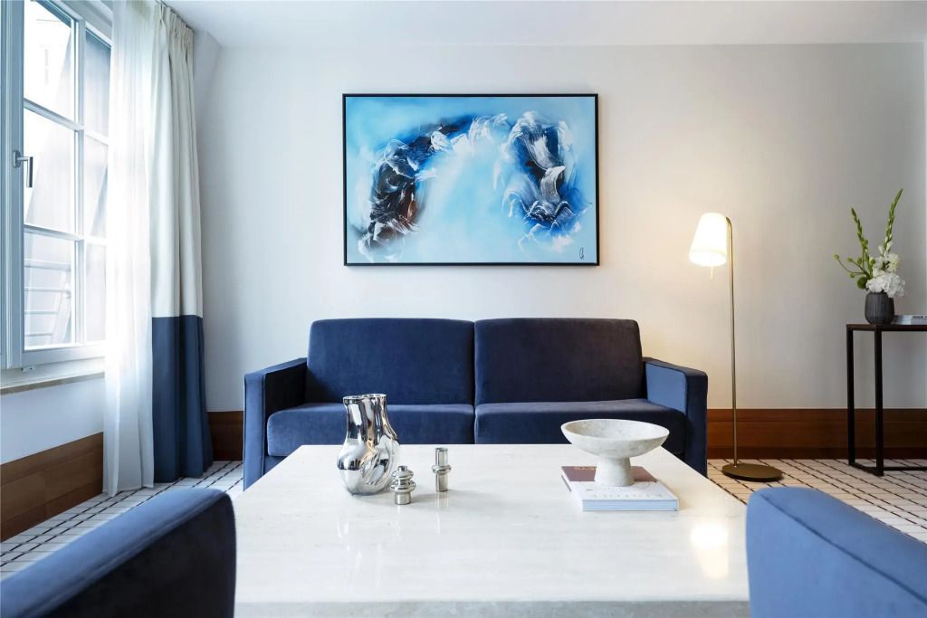 Wohnbereich mit blauer Couch und stilvollem Kunstwerk in der Junior-Suite