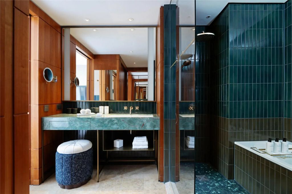 Modernes Badezimmer mit eleganter grüner Fliesenverkleidung und Doppelwaschbecken.