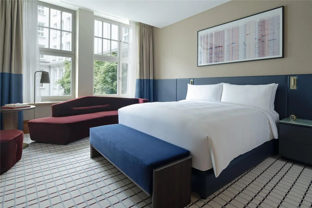 Modernes Einzelzimmer mit großem Fenster und gemütlichem Bett