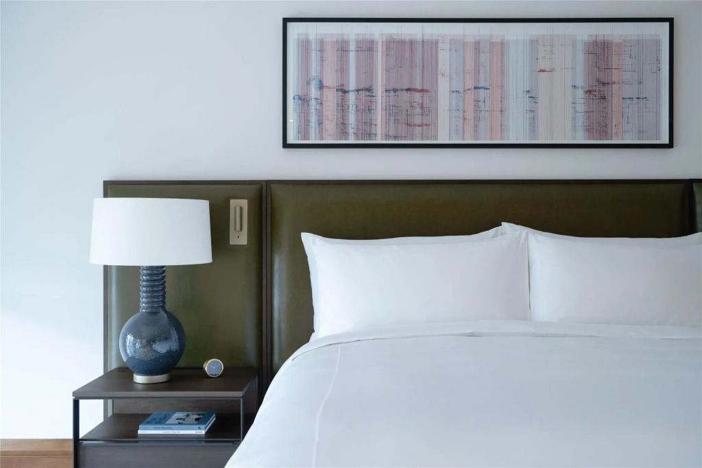 Doppelbett in einem modernen Hotelzimmer mit Kunst an der Wand und eleganter Tischlampe