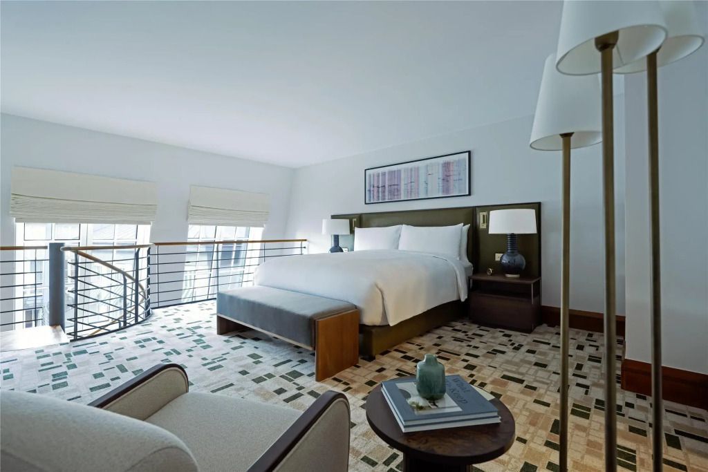 Geräumiges Hotelzimmer mit großem Bett, gemustertem Teppich und Sitzbereich