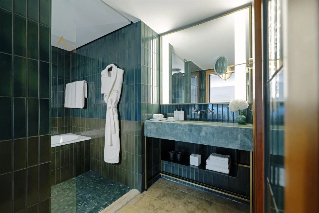 Badezimmer mit grünen Fliesen, breitem Waschtisch und luxuriöser Ausstattung