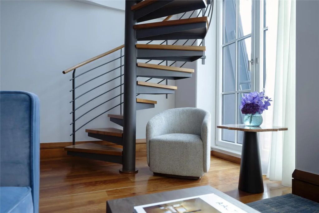 Moderne Wendeltreppe in einem Raum mit Holzfußboden und gemütlichem Sessel