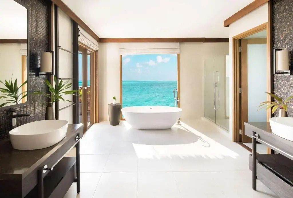 Großzügiges Badezimmer mit freistehender Badewanne und Blick aufs Meer