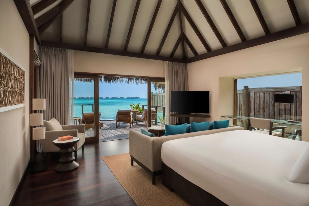 Luxuriöse Wasservilla mit Doppelbett und Blick auf das türkisblaue Meer