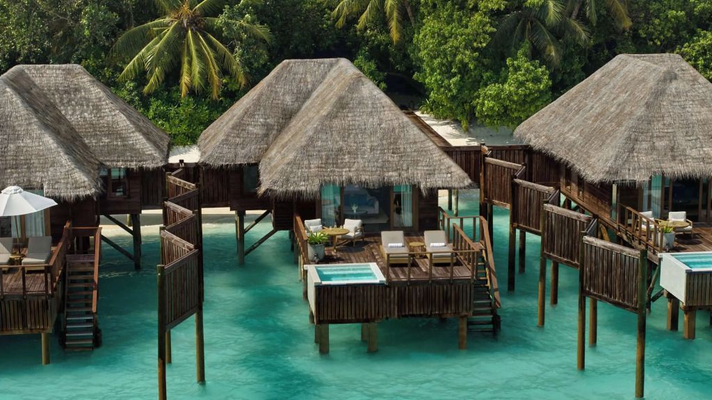 Wasservilla mit Strohdach und privatem Pool auf Stelzen im Meer