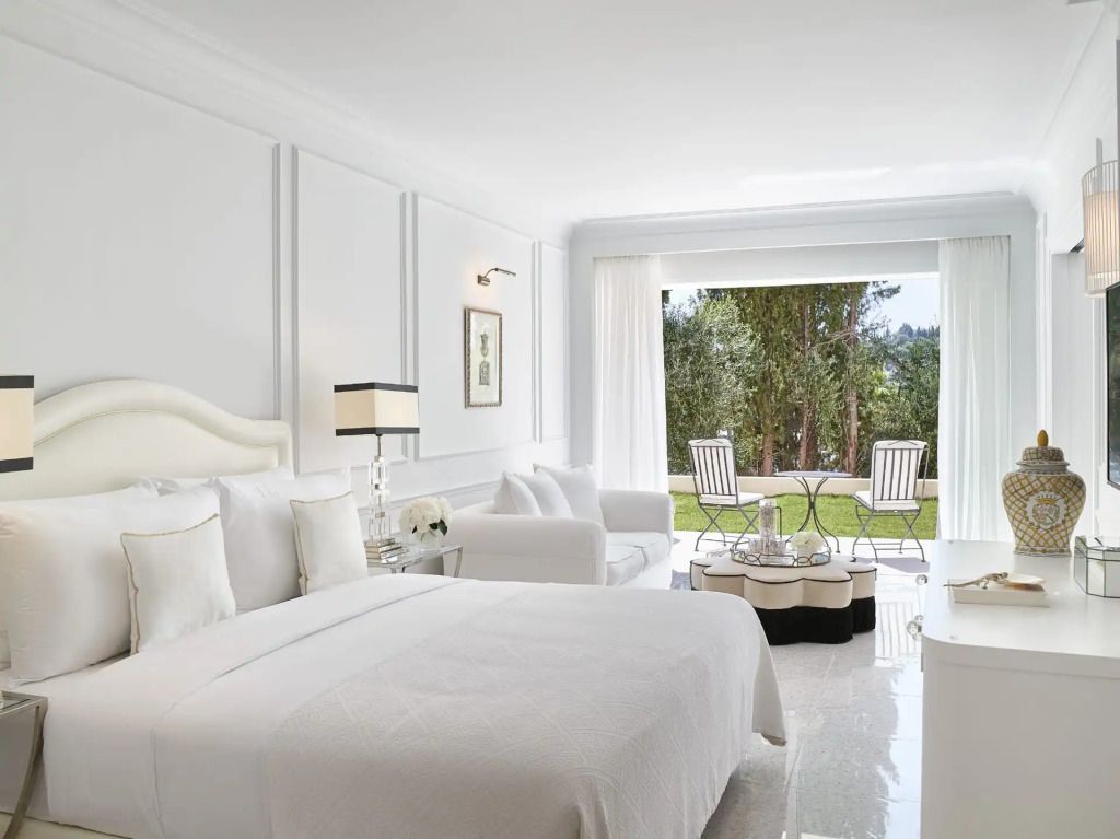 Helles Schlafzimmer mit Doppelbett und Terrasse mit Gartenblick