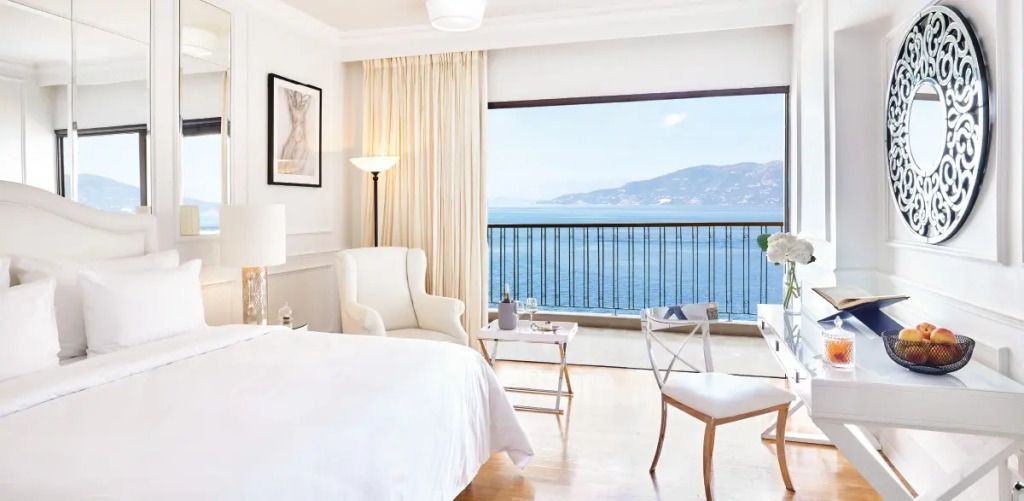 Helles Hotelzimmer mit Doppelbett und Meerblick auf den Balkon