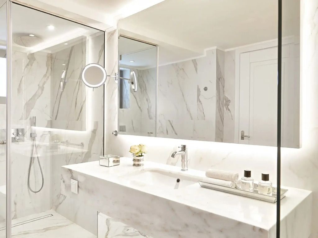 Luxuriöses Badezimmer mit Marmorverkleidung und großem Spiegel im Corfu Imperial Resort.