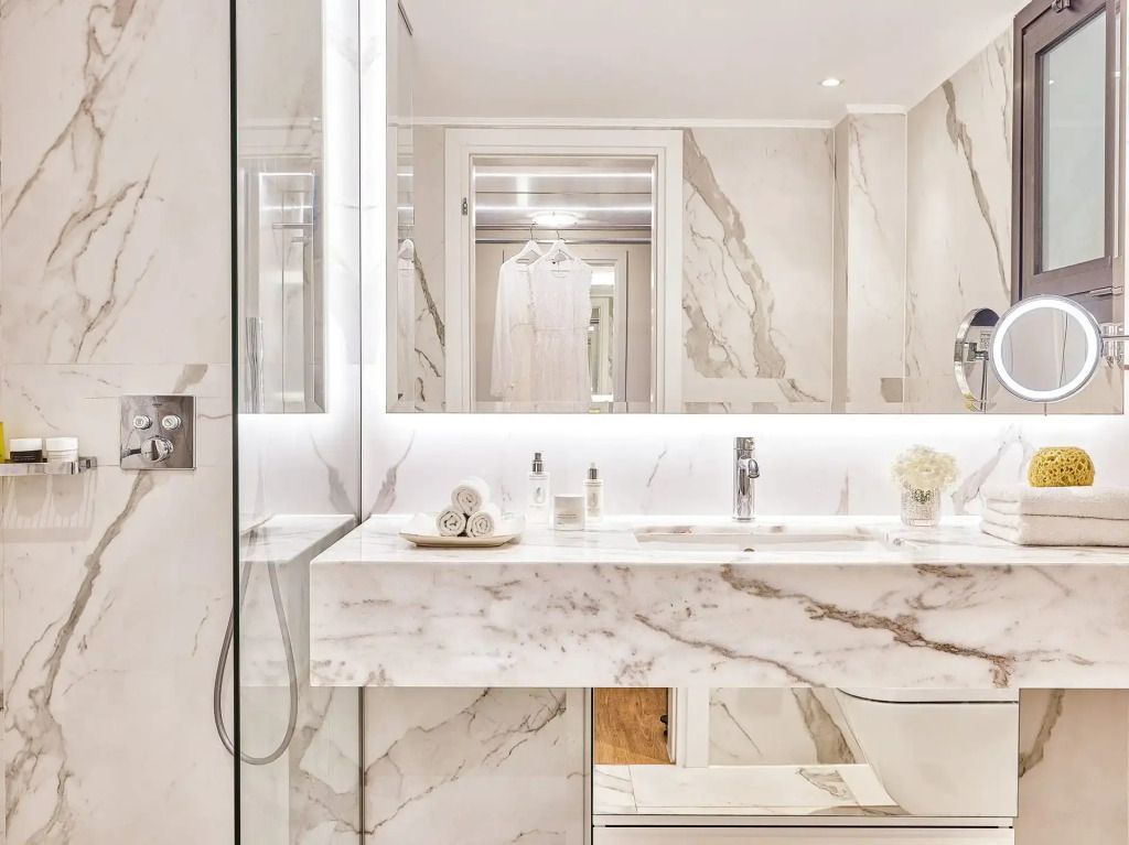 Modernes Badezimmer mit Marmorakzenten und eleganter Beleuchtung im Corfu Imperial Resort.