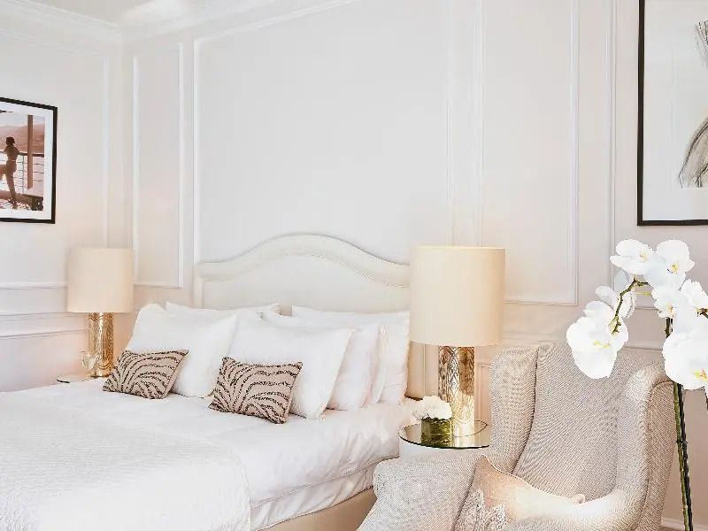 Luxuriöses Doppelbett mit eleganter Beleuchtung und gemütlichem Sessel