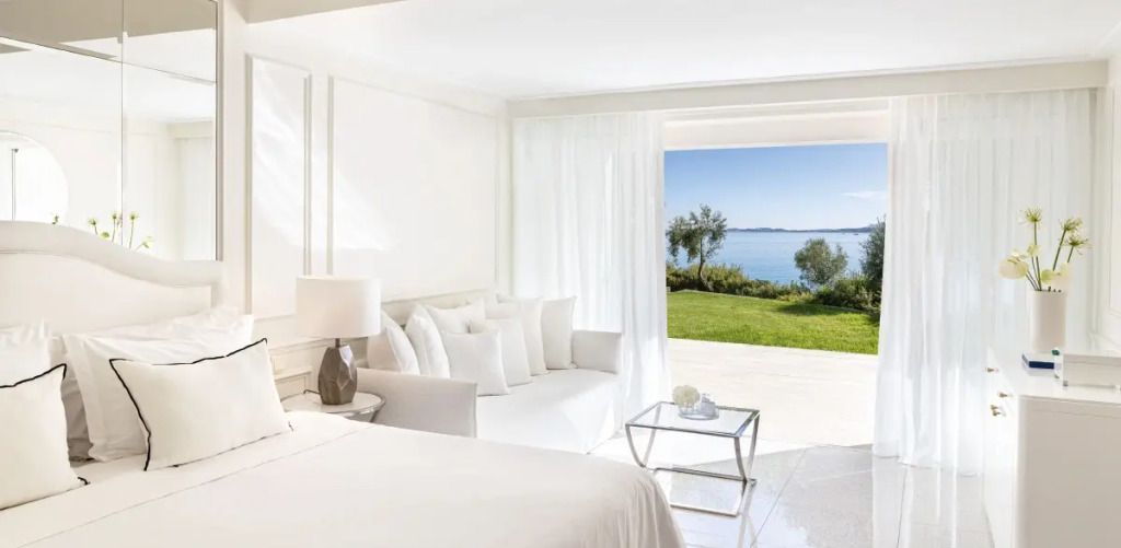 Helle Junior-Suite mit Doppelbett, Blick auf das Meer und grünen Garten
