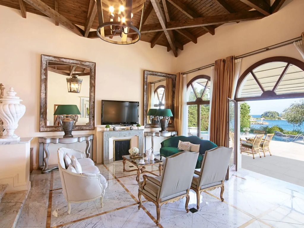 Luxuriöses Wohnzimmer mit hohen Decken, Kamin und großem Fenster mit Meerblick.