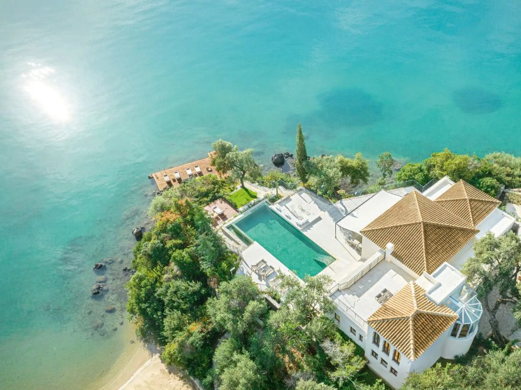 Luftaufnahme des Resorts mit Pool in mediterraner Landschaft und türkisfarbenem Meer.